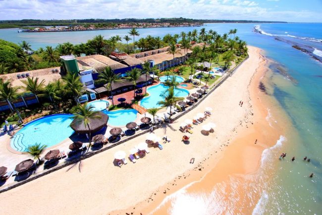 Aérea do resort com detalhes da piscinas e gazebos postas frente mar