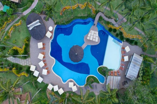 Aérea da piscina do resort com suas cores variadas em meio a natureza
