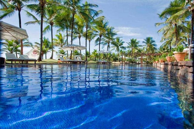 Agua azul da piscina se mistura a natureza exuberante