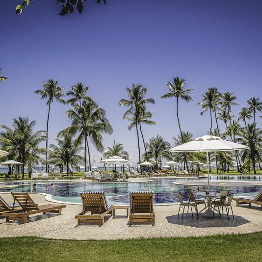 Espreguiçadeiras postas com guarda sóis na piscina