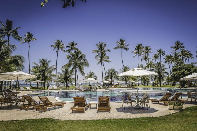 Espreguiçadeiras postas com guarda sóis na piscina